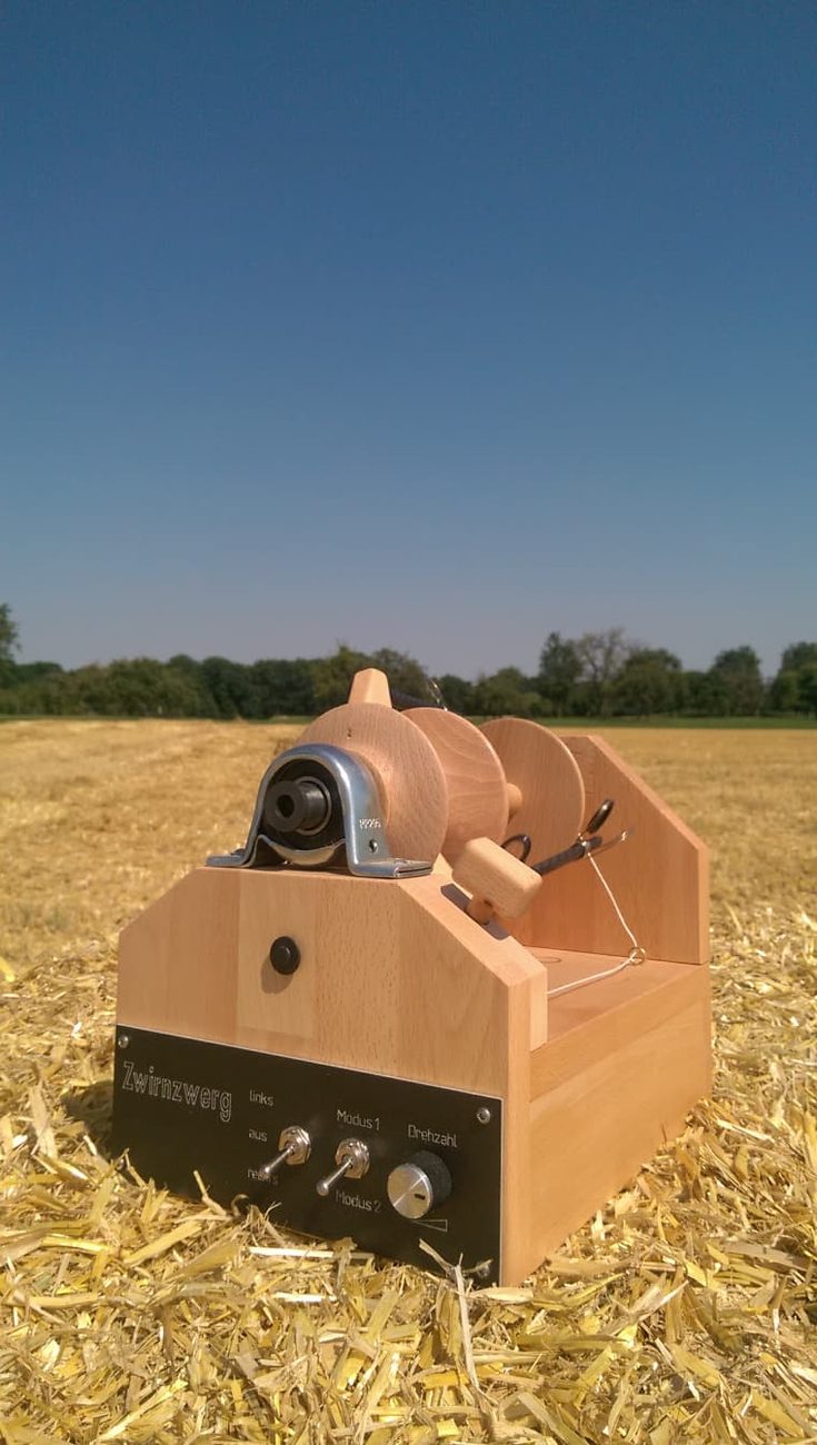 Der Zwirnzwerg – elektrisches Spinngerät aus Buche-Massivholz auf einem abgeernteten Feld